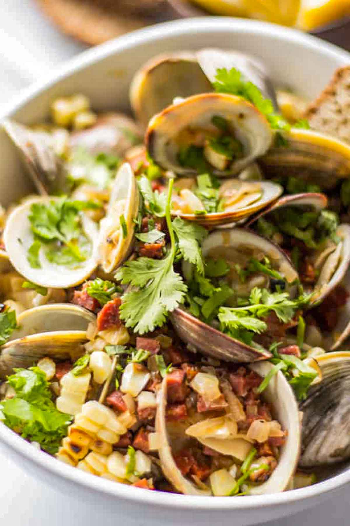 A bowl of steamed clams mixed with corn, diced chorizo, and fresh cilantro.