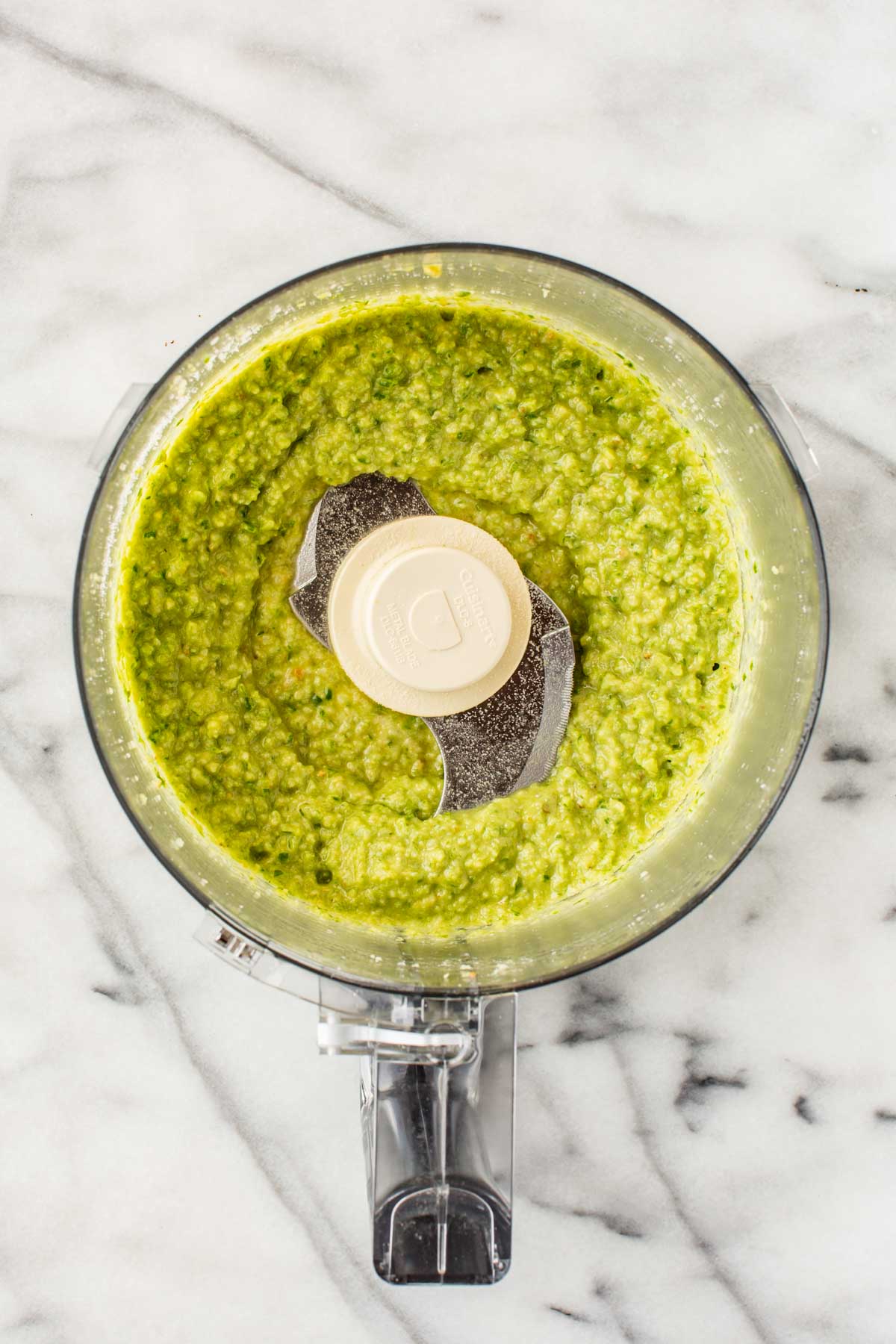 Smooth and creamy garlic scape pesto with a vibrant green hue, freshly processed and ready to serve.