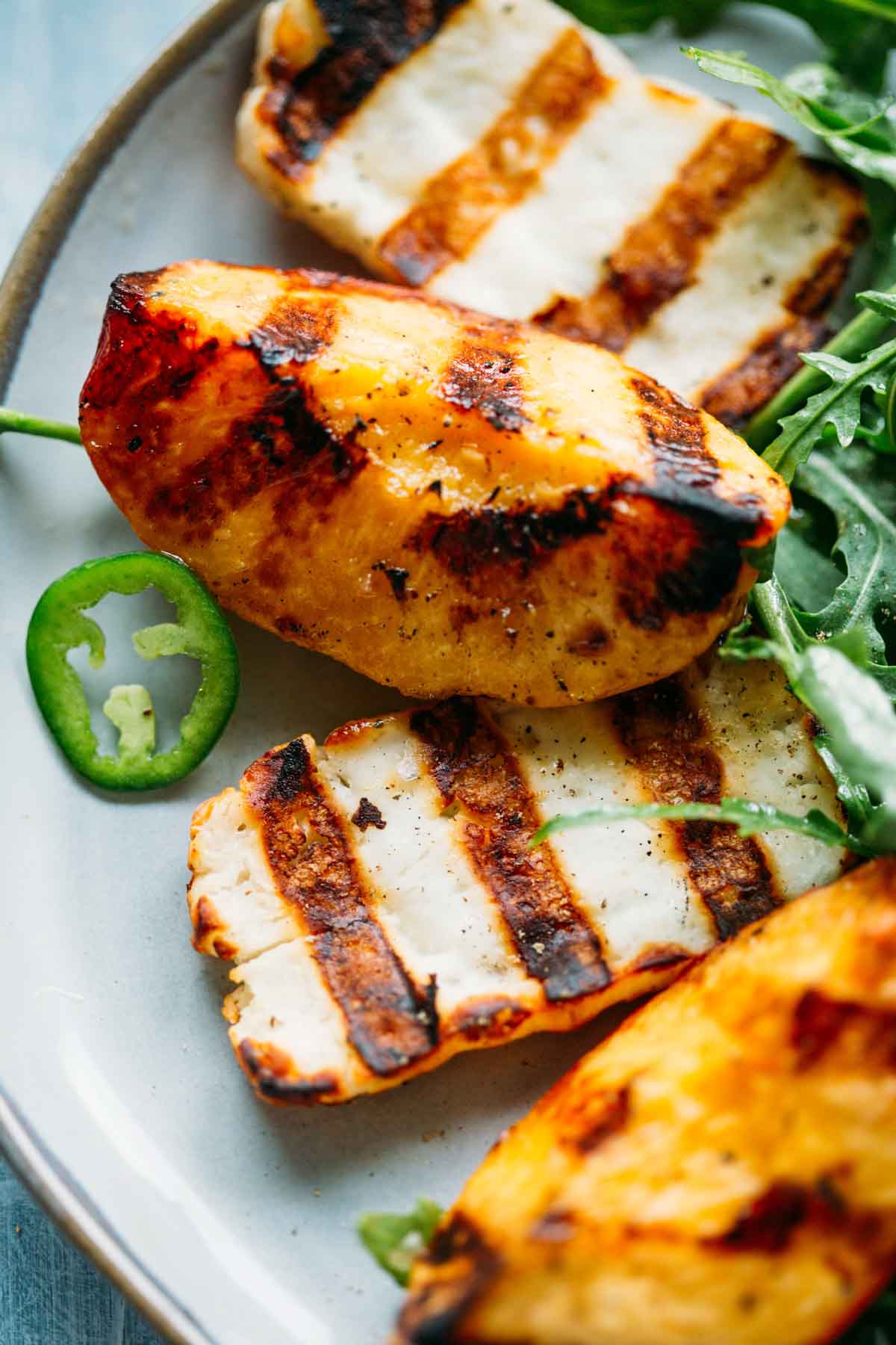 Close-up of juicy grilled peach and charred halloumi slice with fresh arugula.