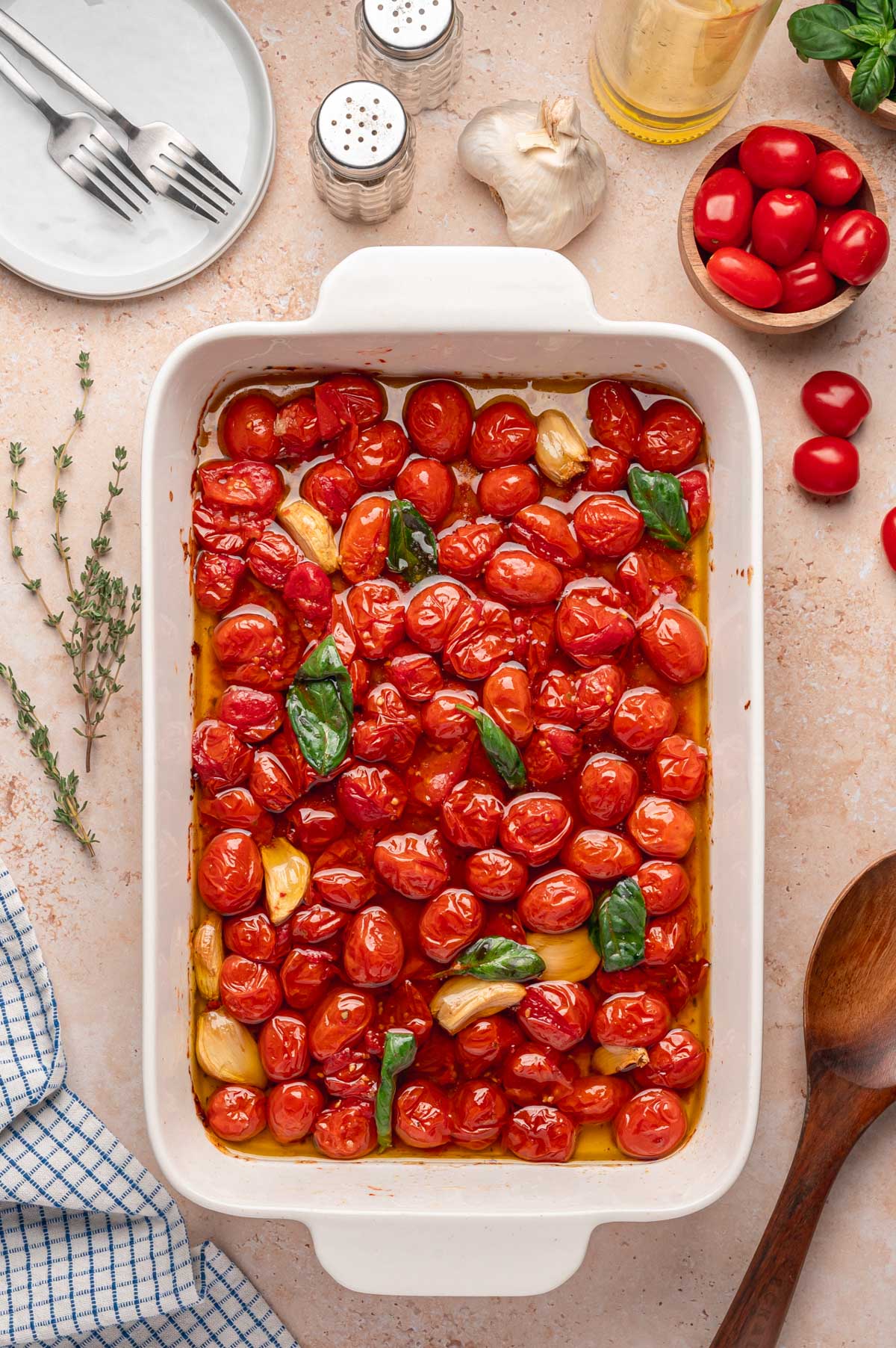 Finished tomato confit in a dish surrounded by fresh ingredients and kitchenware.