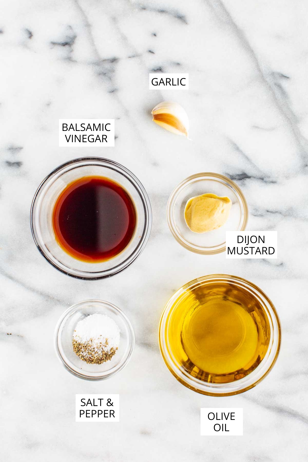Labeled flat lay of vinaigrette ingredients: balsamic vinegar, olive oil, Dijon mustard, garlic, salt, and pepper.