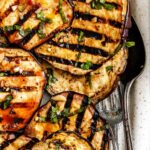 Zoomed-in detail of the grilled eggplant, highlighting char marks and glistening balsamic marinade with herbs.