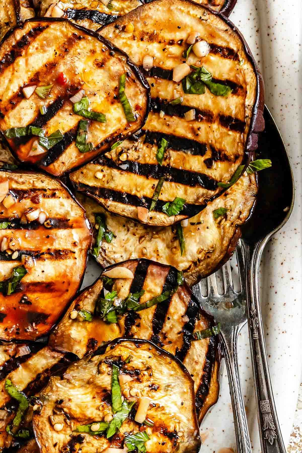 Zoomed-in detail of the grilled eggplant, highlighting char marks and glistening balsamic marinade with herbs.