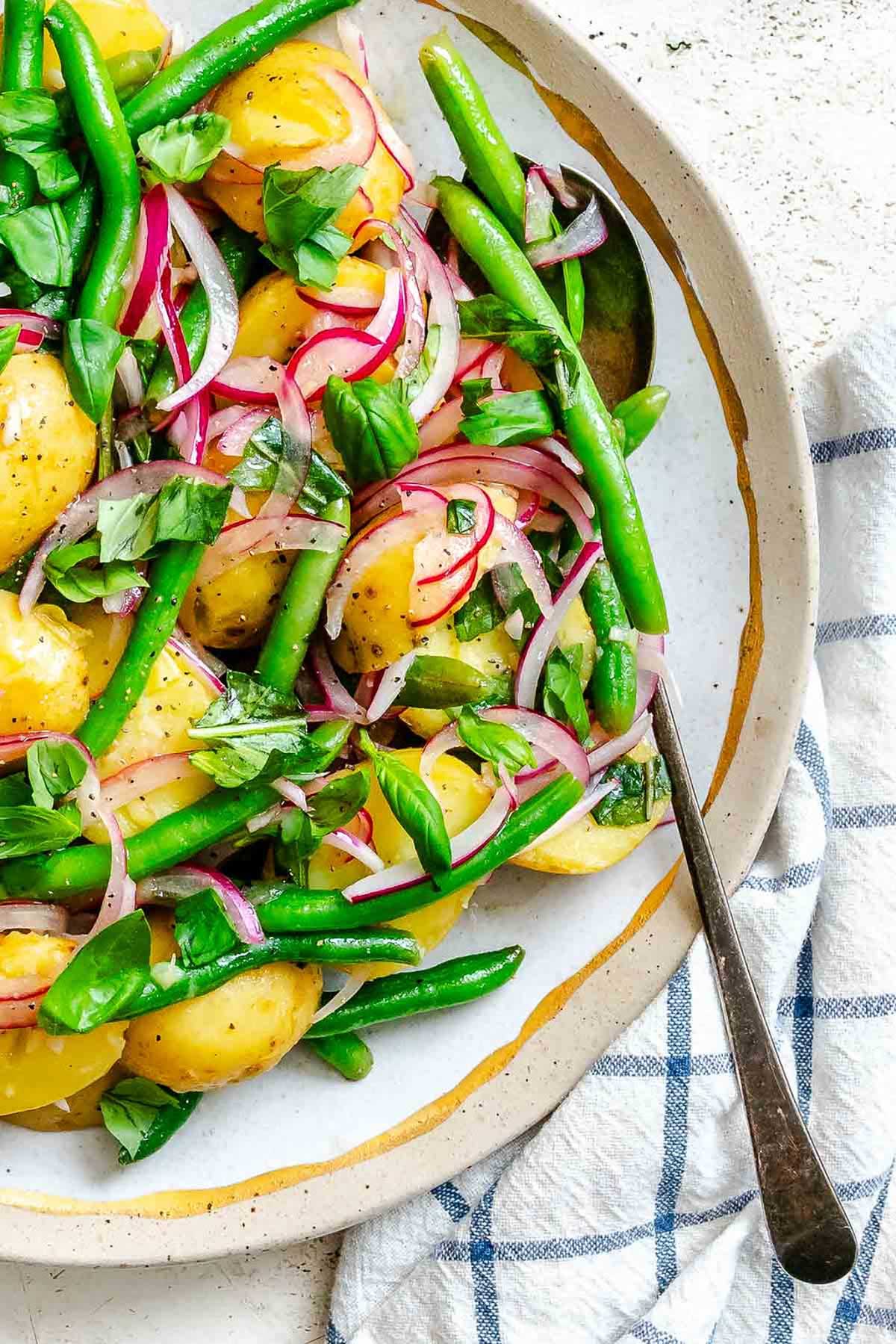 Zoomed-in section of the salad highlighting the glossiness of the vinaigrette on crisp green beans, tender potatoes, and sliced onions.