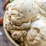 Close-up of creamy rosemary brown butter pecan ice cream in a bowl, highlighting flecks of pecans and brown butter speckles throughout.