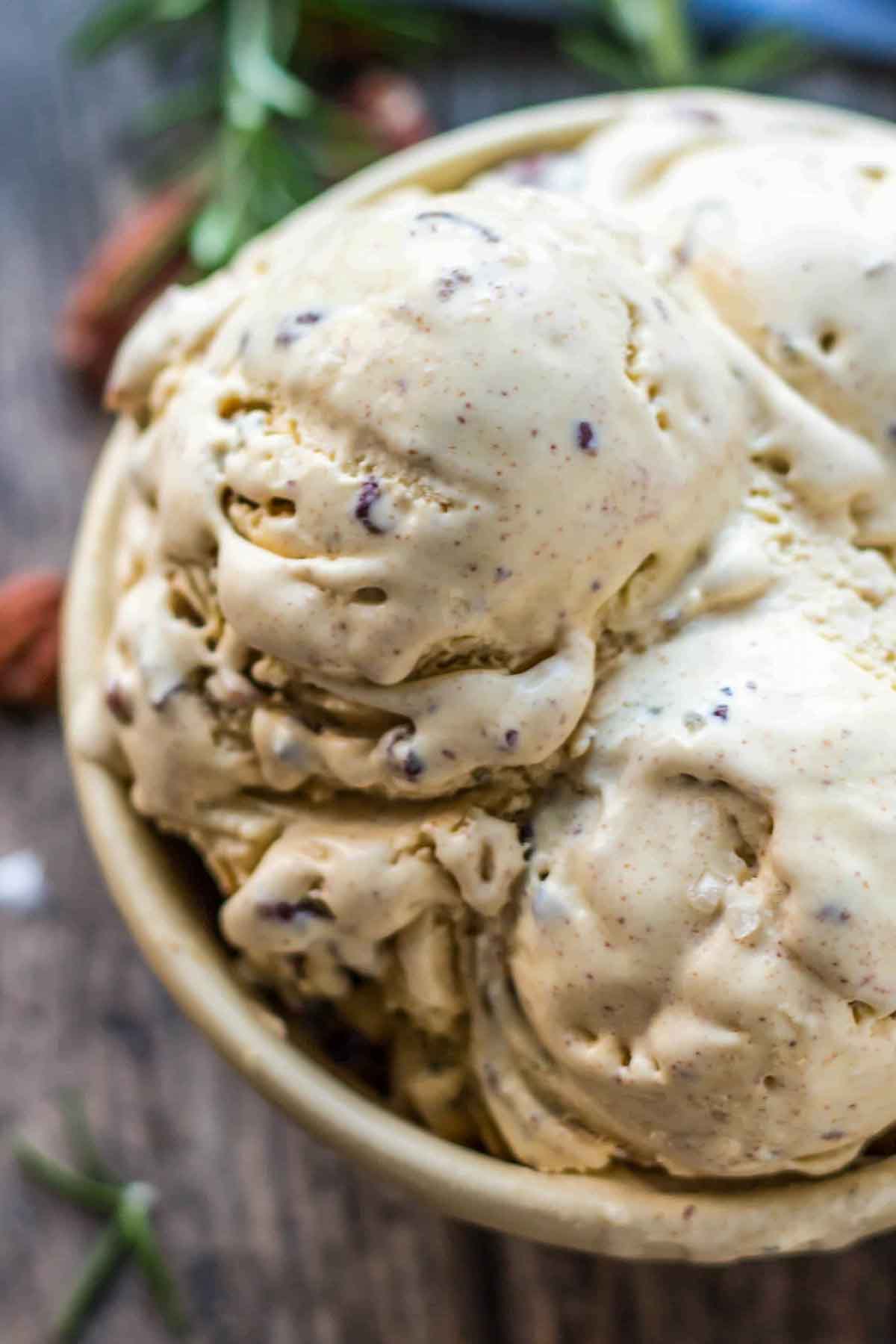 Close-up of creamy rosemary brown butter pecan ice cream in a bowl, highlighting flecks of pecans and brown butter speckles throughout.