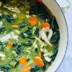 Another close view of the soup in the pot highlighting the vibrant green broth, wilted kale, and white beans.