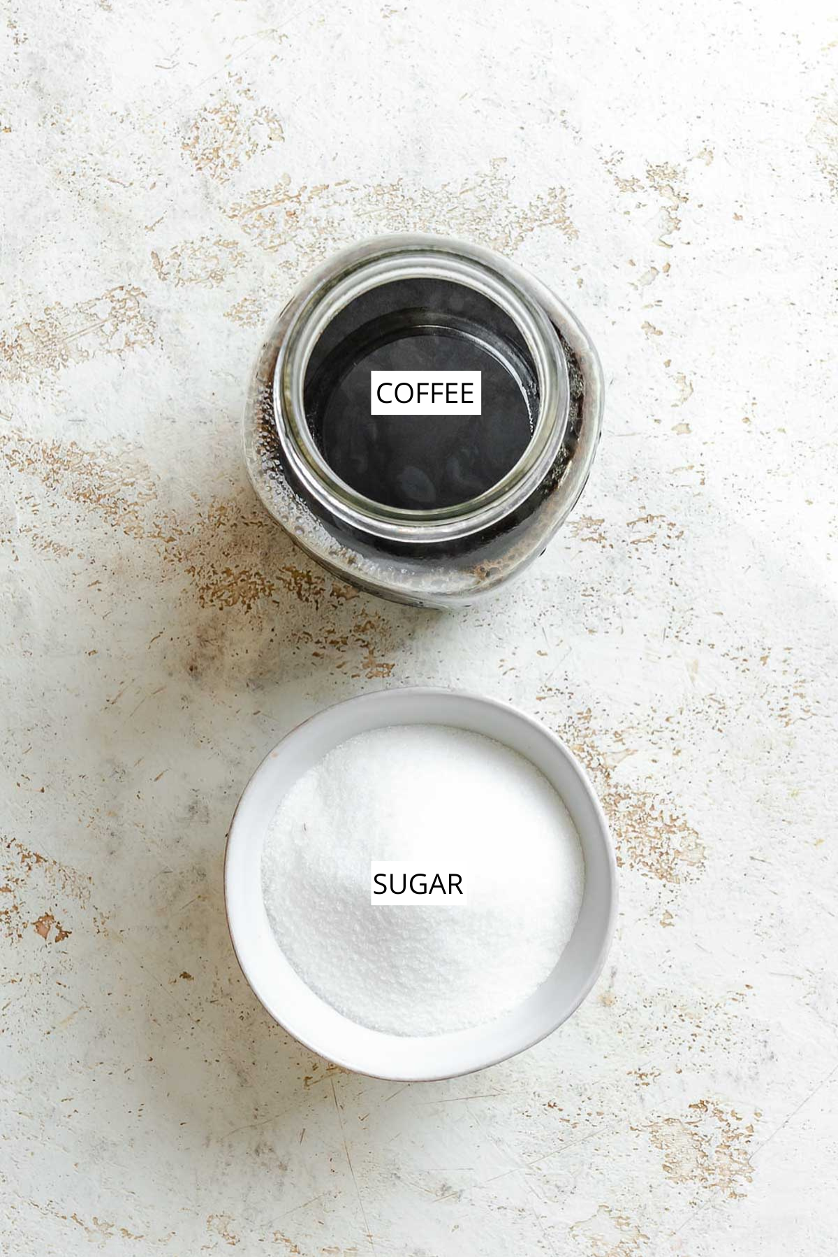 Overhead photo of labeled ingredients: a jar of brewed coffee and a bowl of granulated sugar.