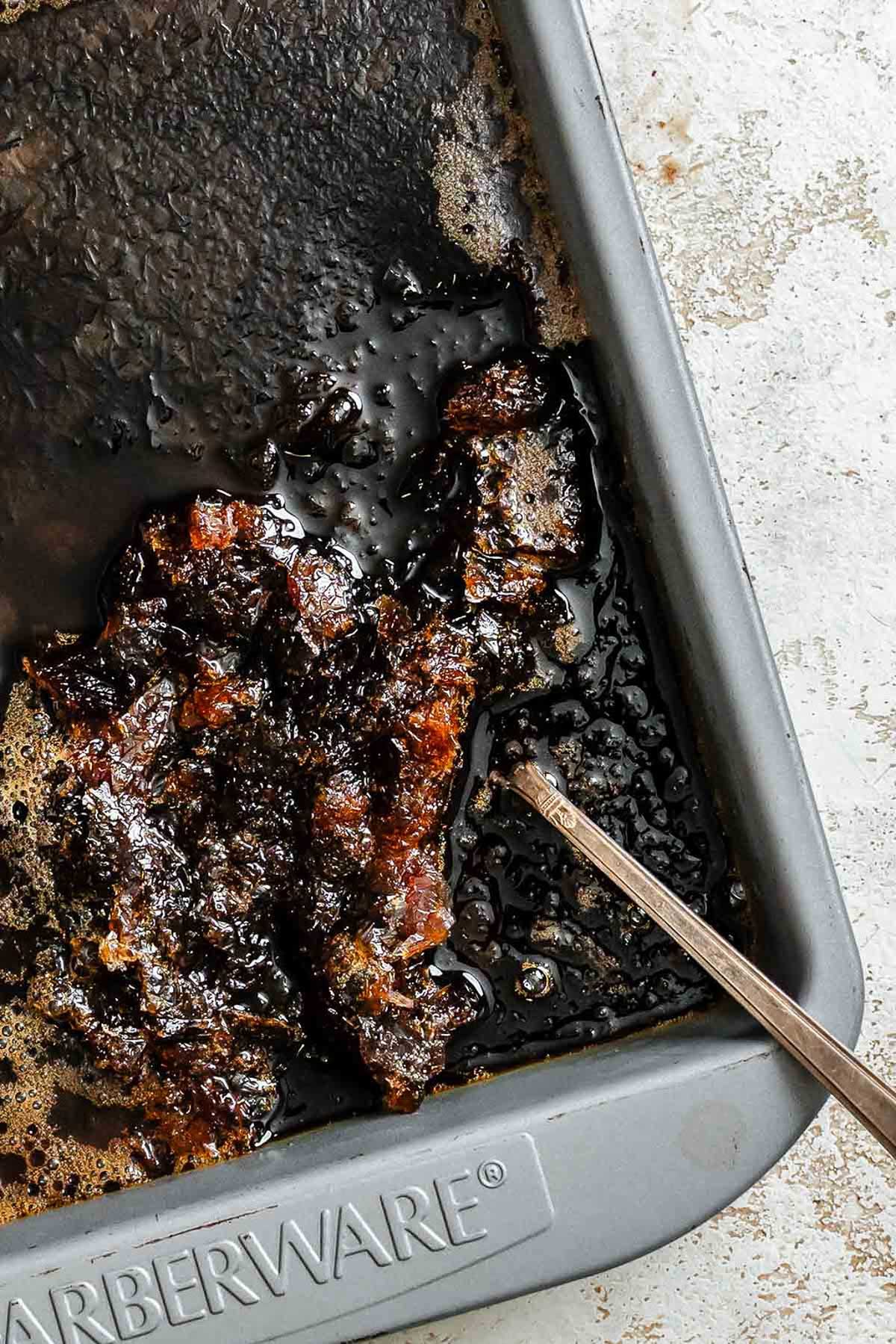 Partially frozen coffee granita being scraped with a fork inside a pan.
