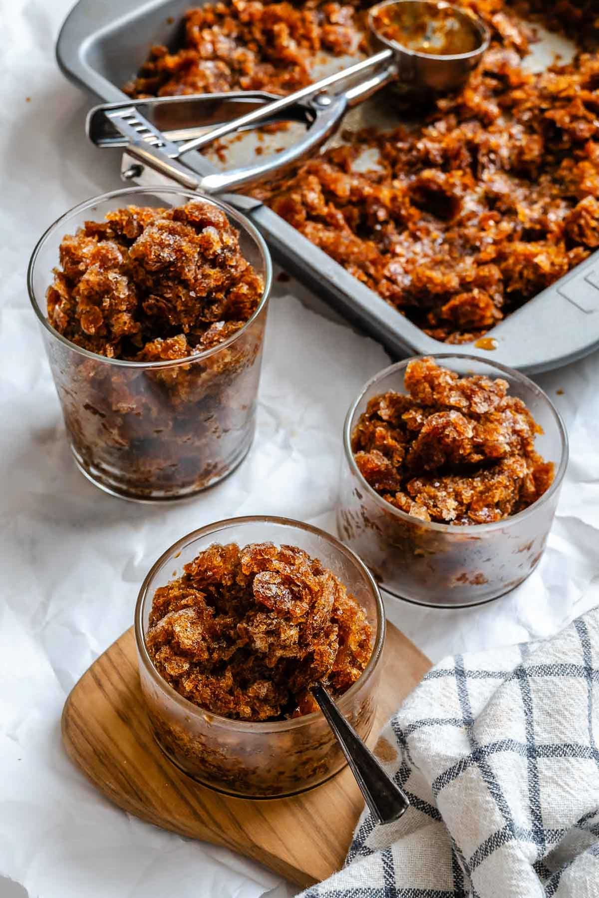 Overhead shot of multiple glasses of coffee granita with a pan of scraped crystals nearby.