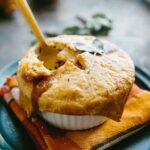Ramekin of baked mini turkey pot pie with a spoon breaking into the crust, revealing the rich turkey and vegetable filling inside.