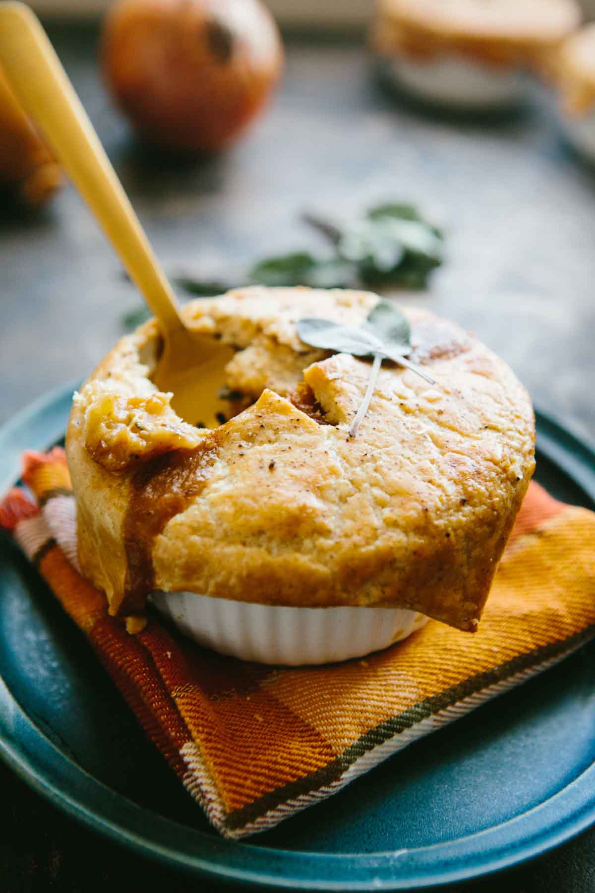 Ramekin of baked mini turkey pot pie with a spoon breaking into the crust, revealing the rich turkey and vegetable filling inside.