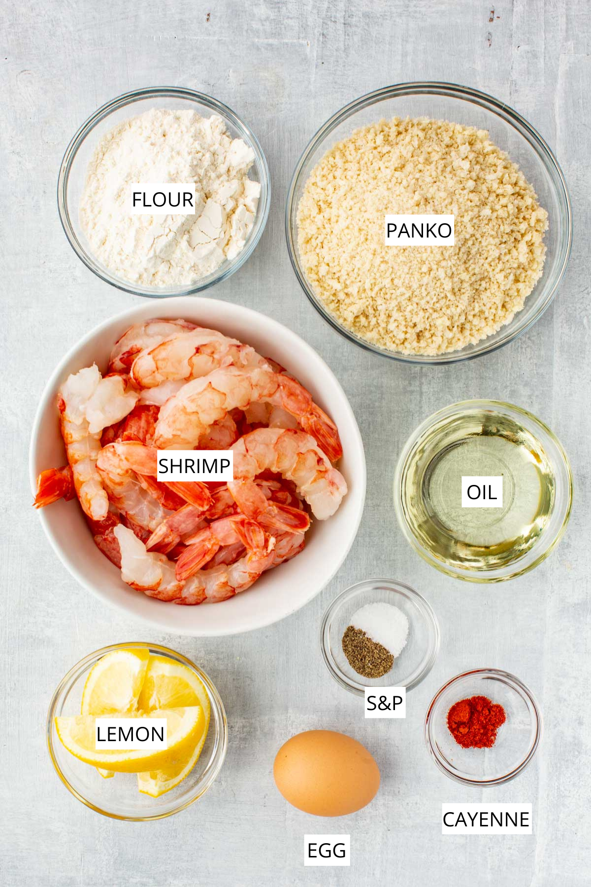 Overhead view of fried shrimp on a blue plate with a small bowl of cocktail sauce and lemon wedges on a wooden board.