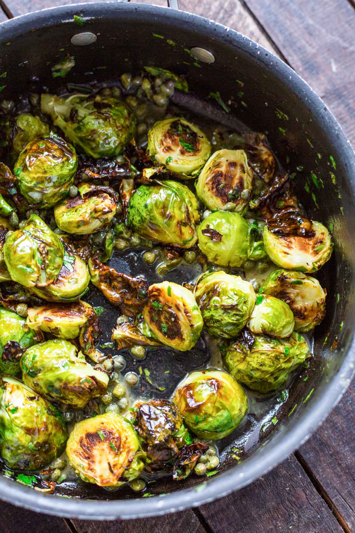 Brussels sprouts seared and caramelized in a skillet with butter, anchovies, and capers just before serving.