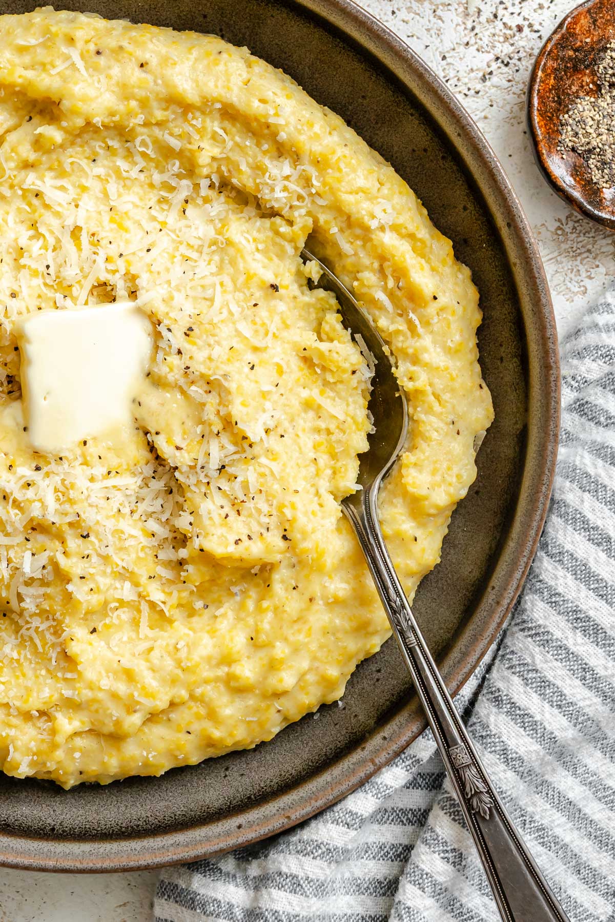 Close-up of warm polenta with melted butter and grated parmesan on top, showing its smooth texture.