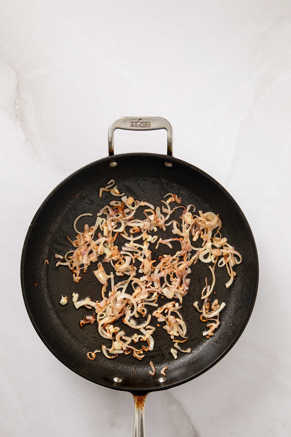 Thinly sliced shallots sautéing in pancetta fat until lightly golden brown.