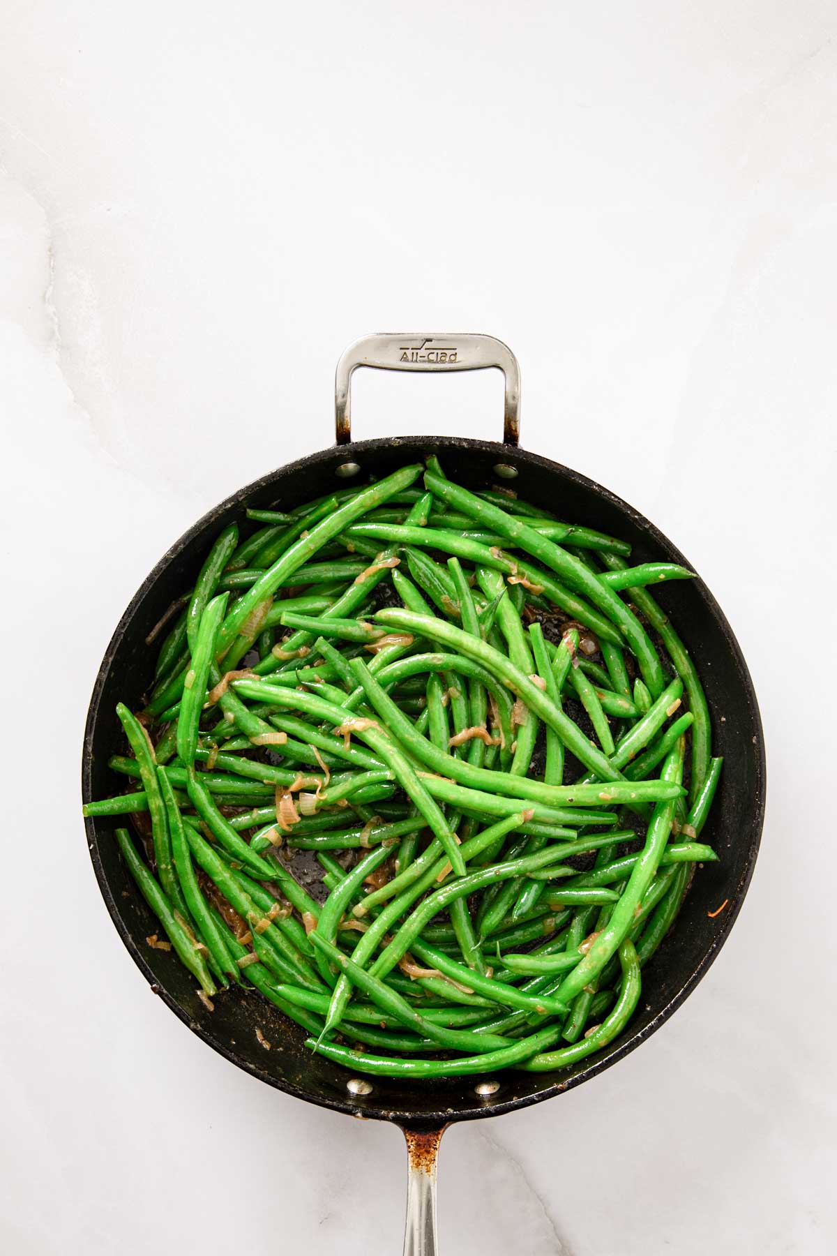 Green beans tossed in the skillet with shallots and sauce until evenly coated.