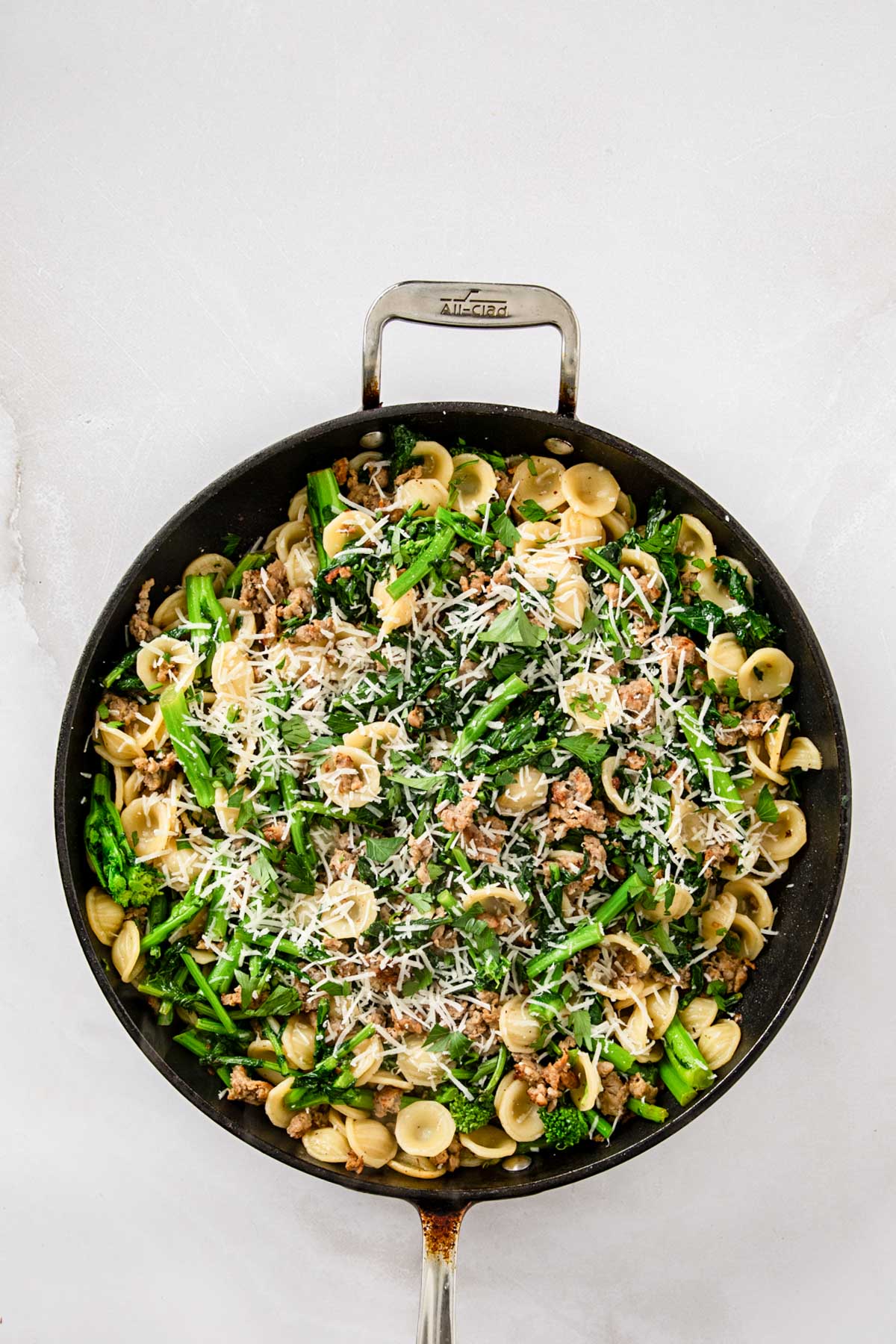 Orecchiette pasta tossed with sausage, broccoli rabe, and grated cheese in a large skillet.