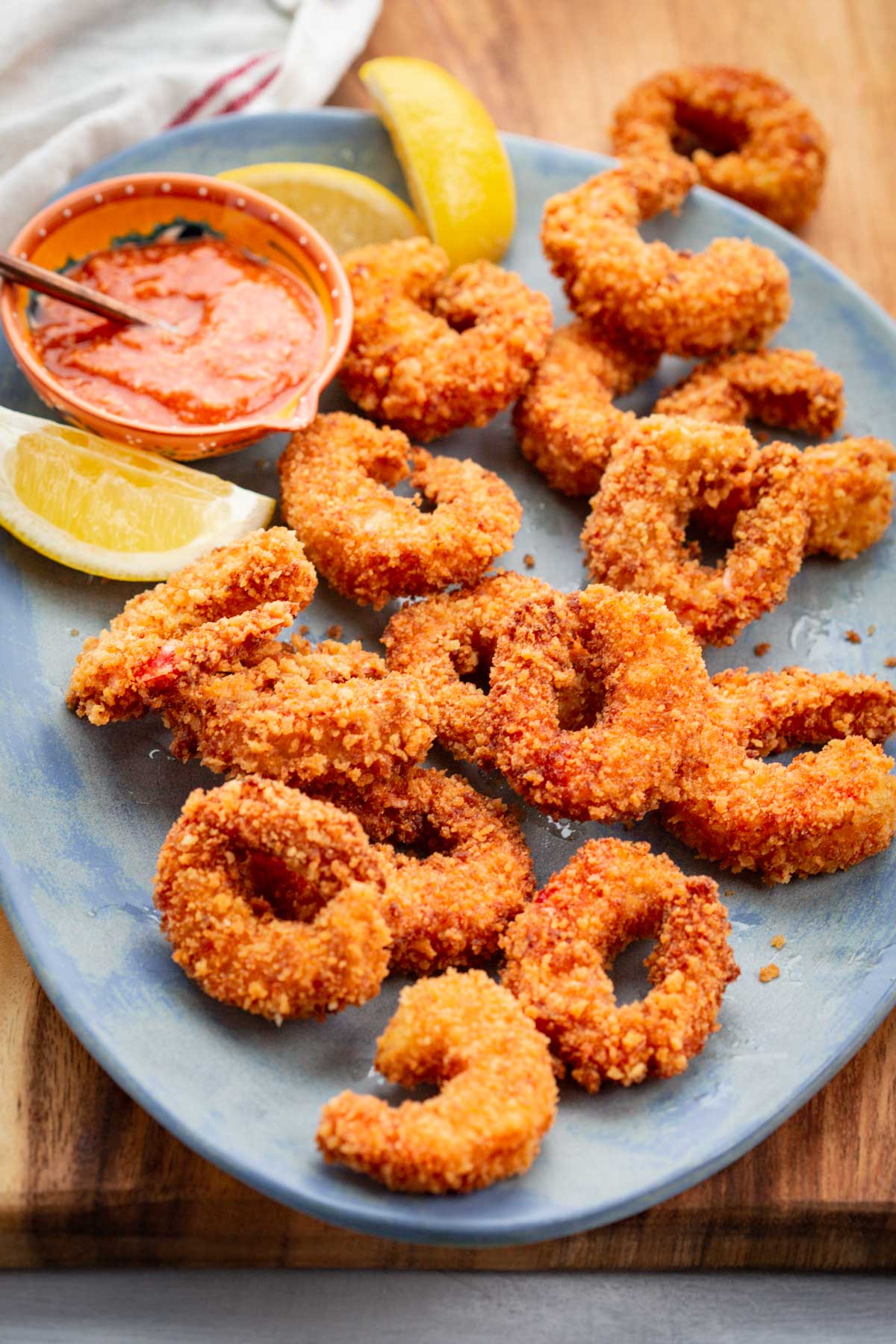 Angled shot of golden brown fried shrimp on a platter showing texture of the crust.