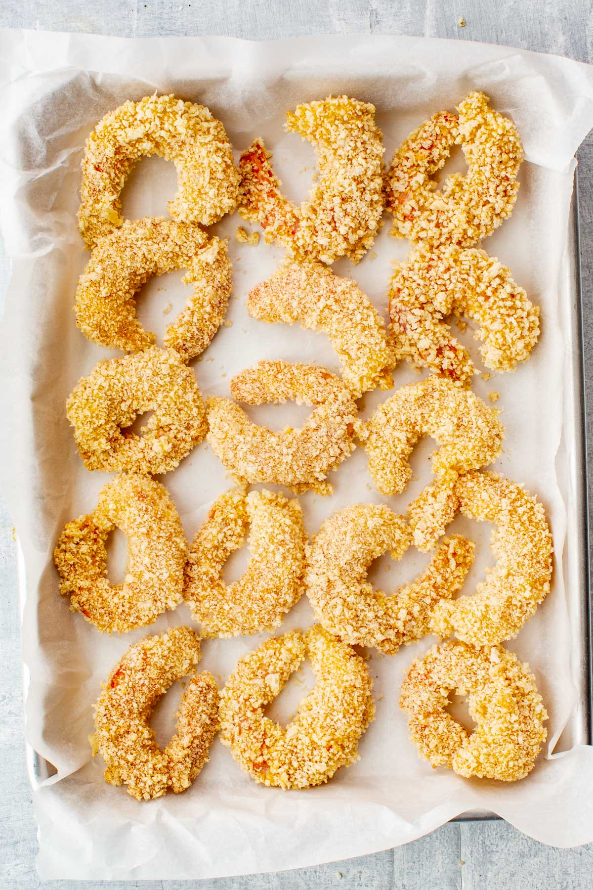 Step-by-step view showing shrimp being dipped in flour, egg, and then panko breadcrumbs for coating.