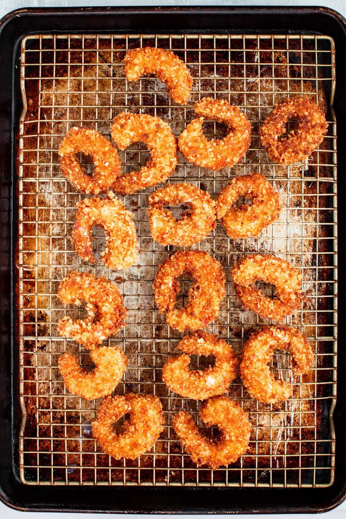 Breaded shrimp arranged on a parchment-lined baking sheet before frying.