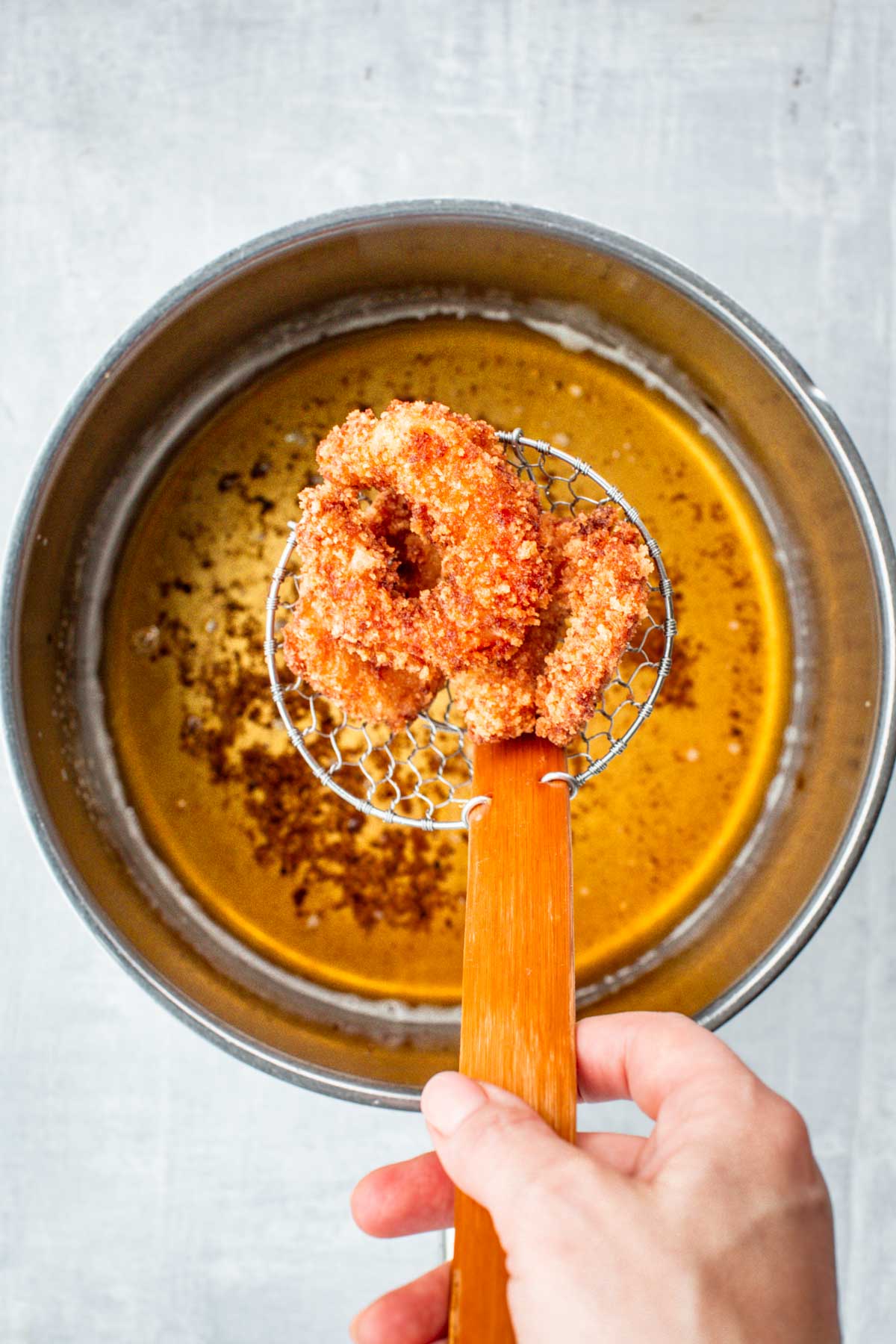Crispy golden brown shrimp cooling on a wire rack after frying.