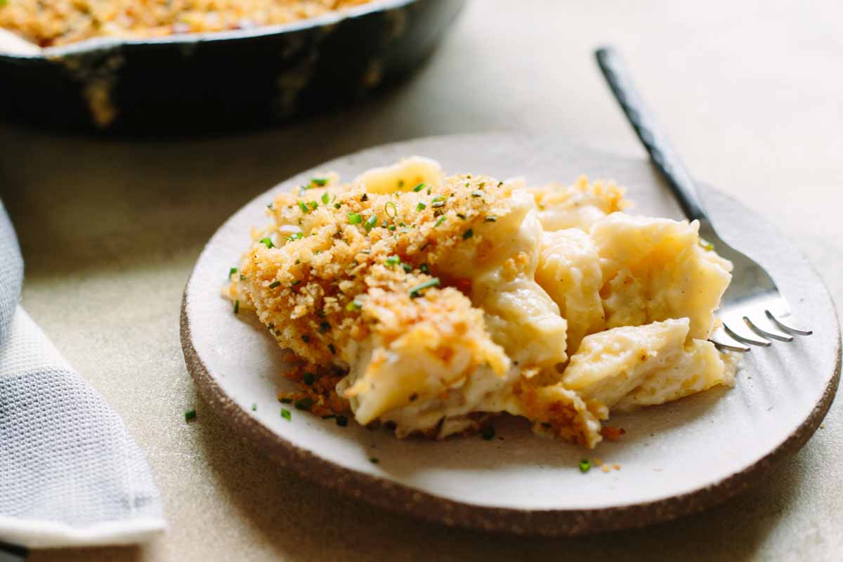 Plated serving of cheesy macaroni with crisp breadcrumbs and fresh chives.