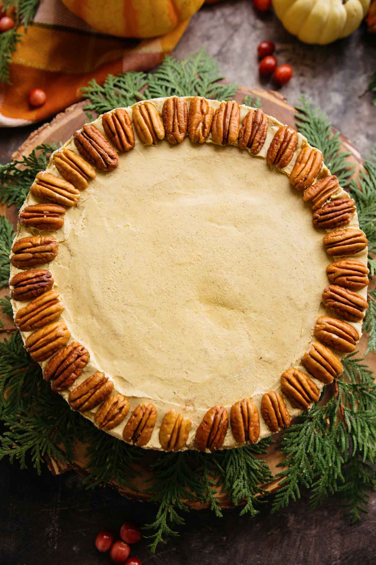 Top-down view of the whole vegan pumpkin cheesecake topped with pecans arranged in a circular pattern.