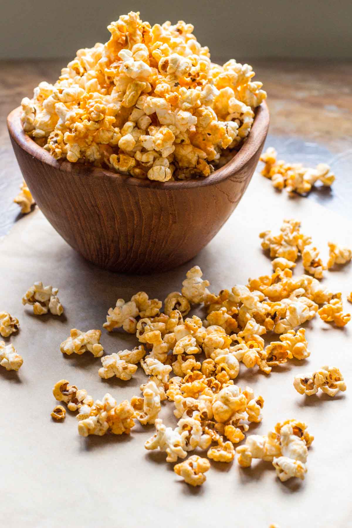 Close-up of caramelized buffalo popcorn in a wooden bowl with loose pieces around.