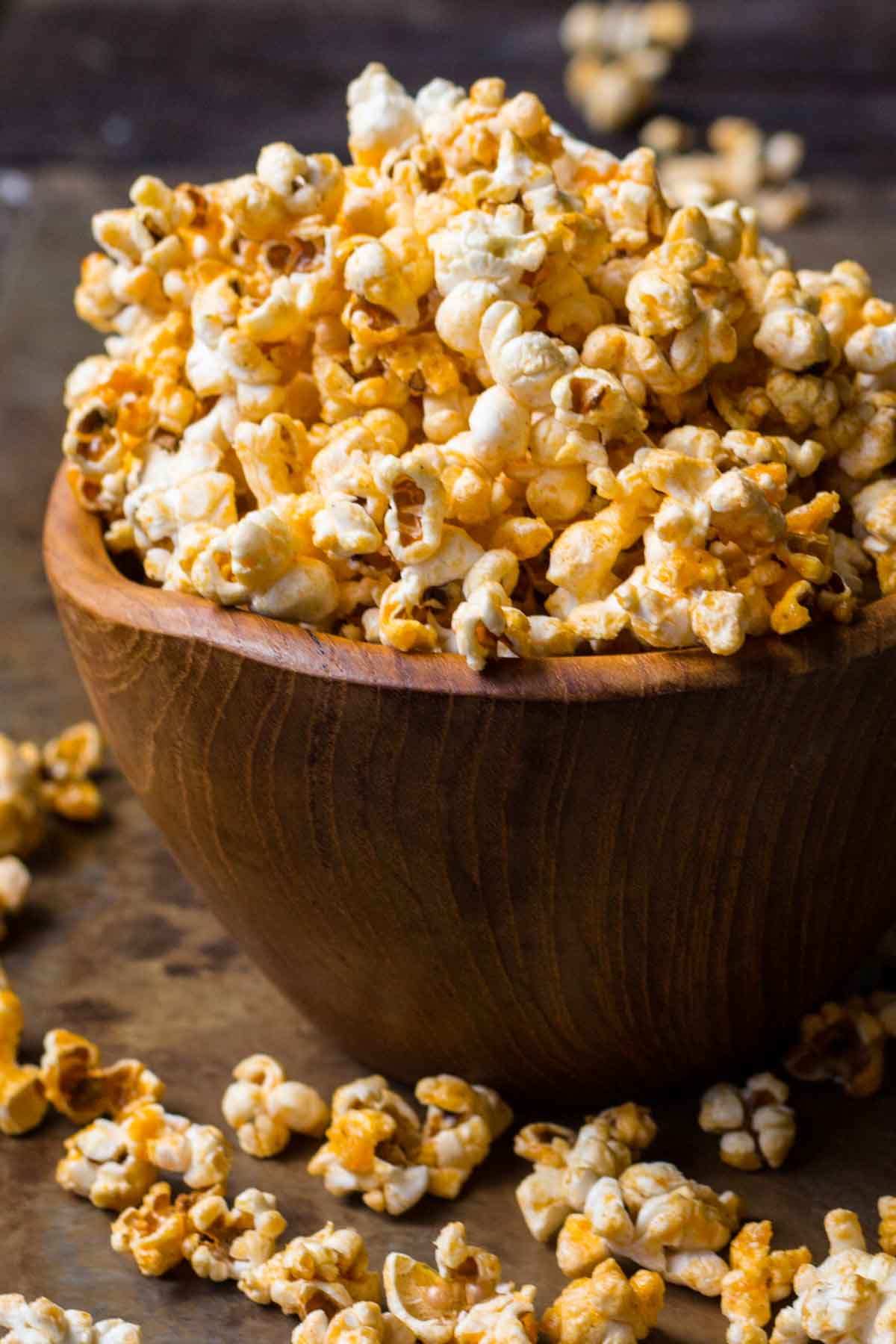 Large wooden bowl filled with honey butter buffalo popcorn showing golden coating.