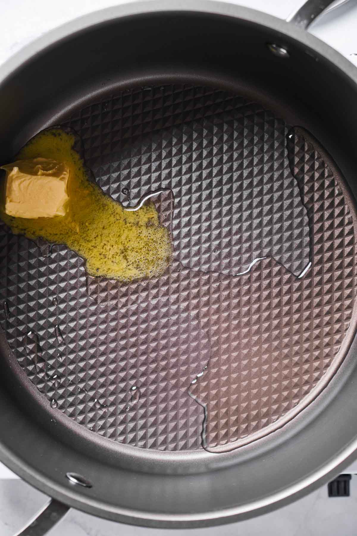 Butter melting in oil inside a nonstick pot, beginning the process of popping popcorn.