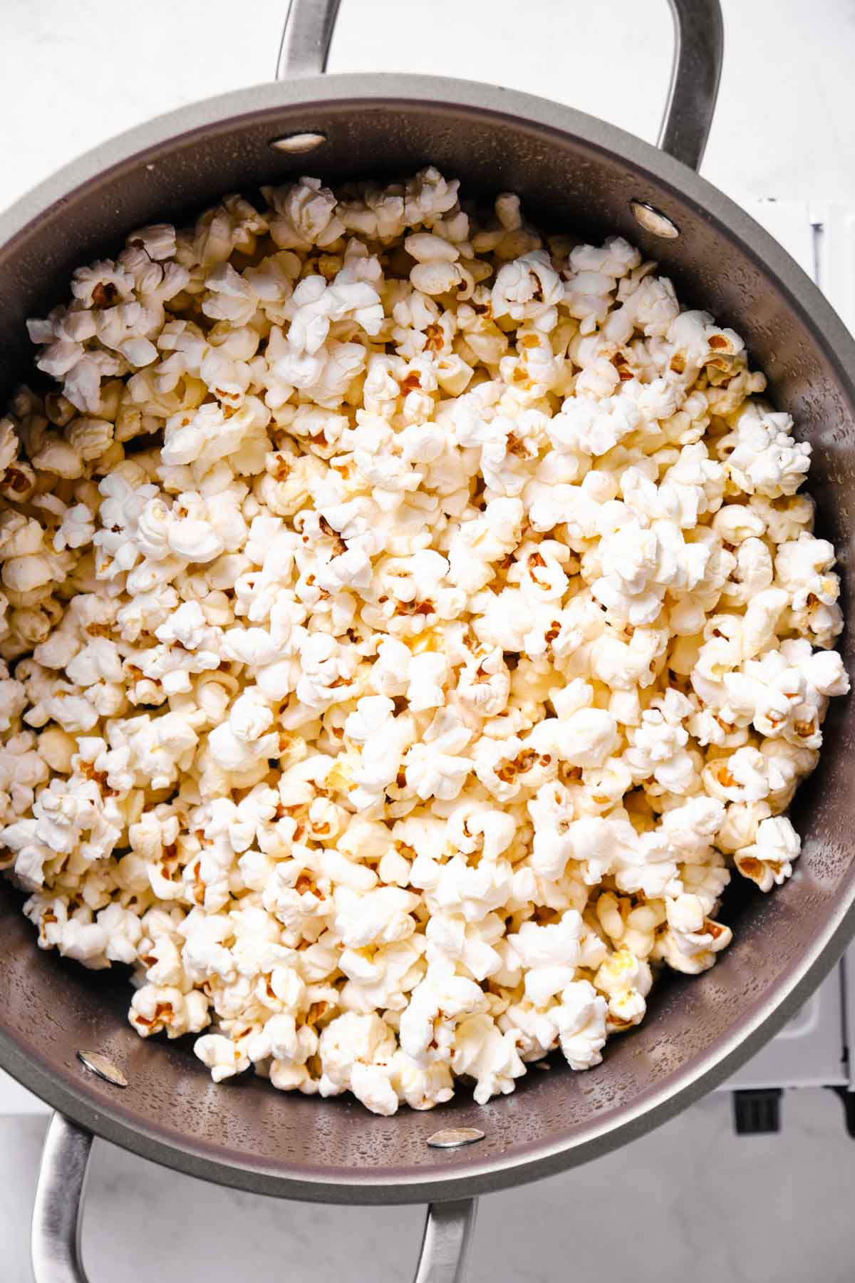 Freshly popped corn filling a large pot after being cooked on the stove.