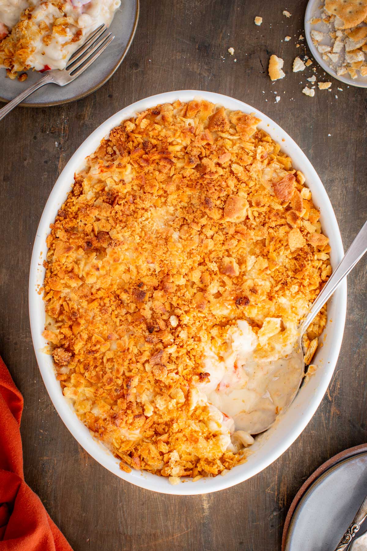 An overhead shot of the baked lobster mac and cheese in an oval dish with a golden Ritz cracker topping and a serving scooped out.