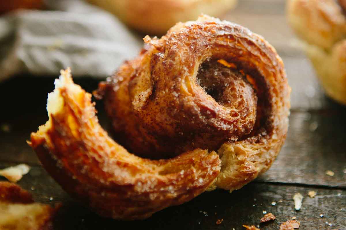 A close up of a morning bun pulled apart, highlighting the tender interior, caramelized edges, and flaky layers.