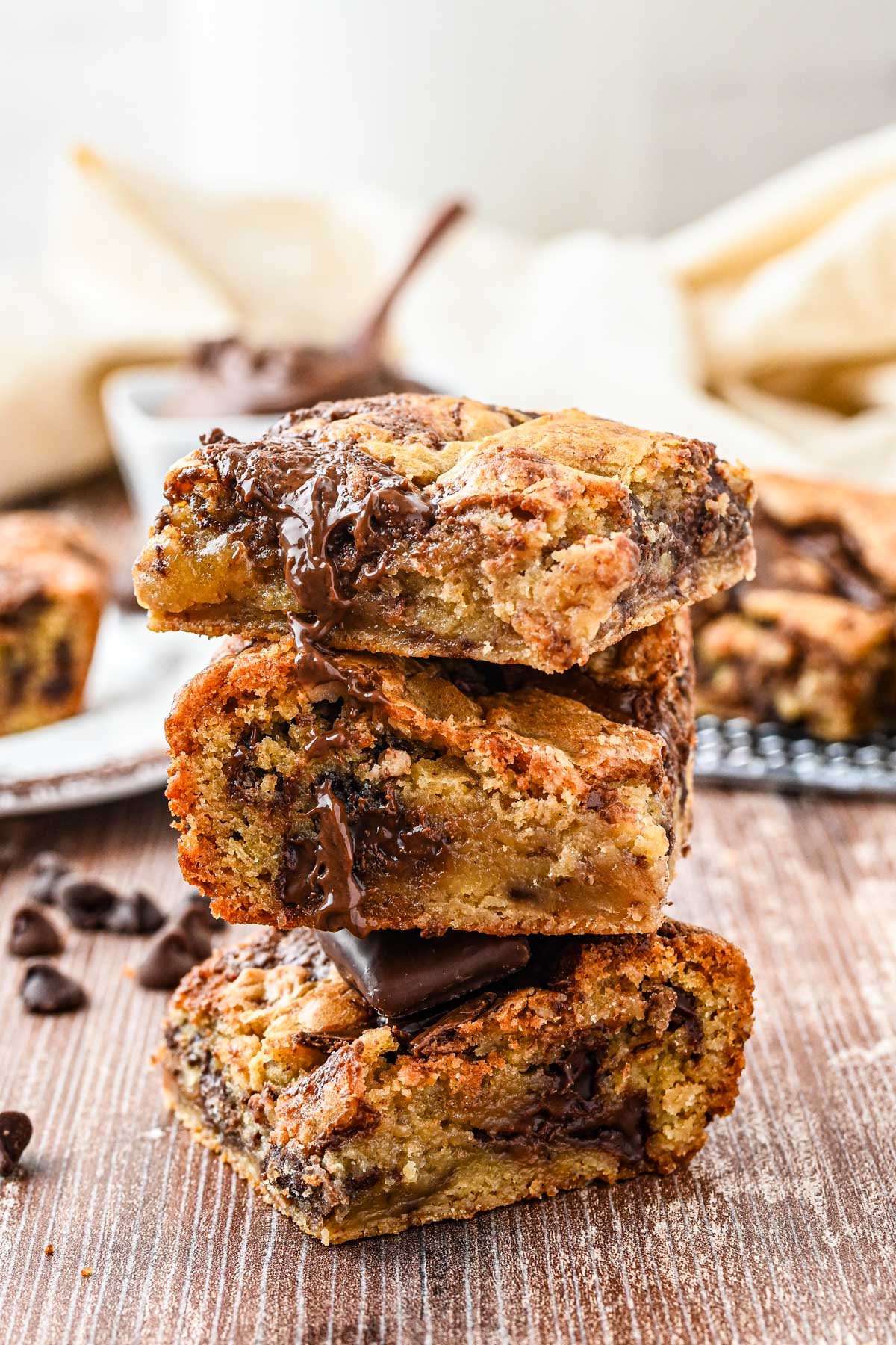 Three blondies stacked on top of each other, showing their gooey centers and melted chocolate running down the sides.