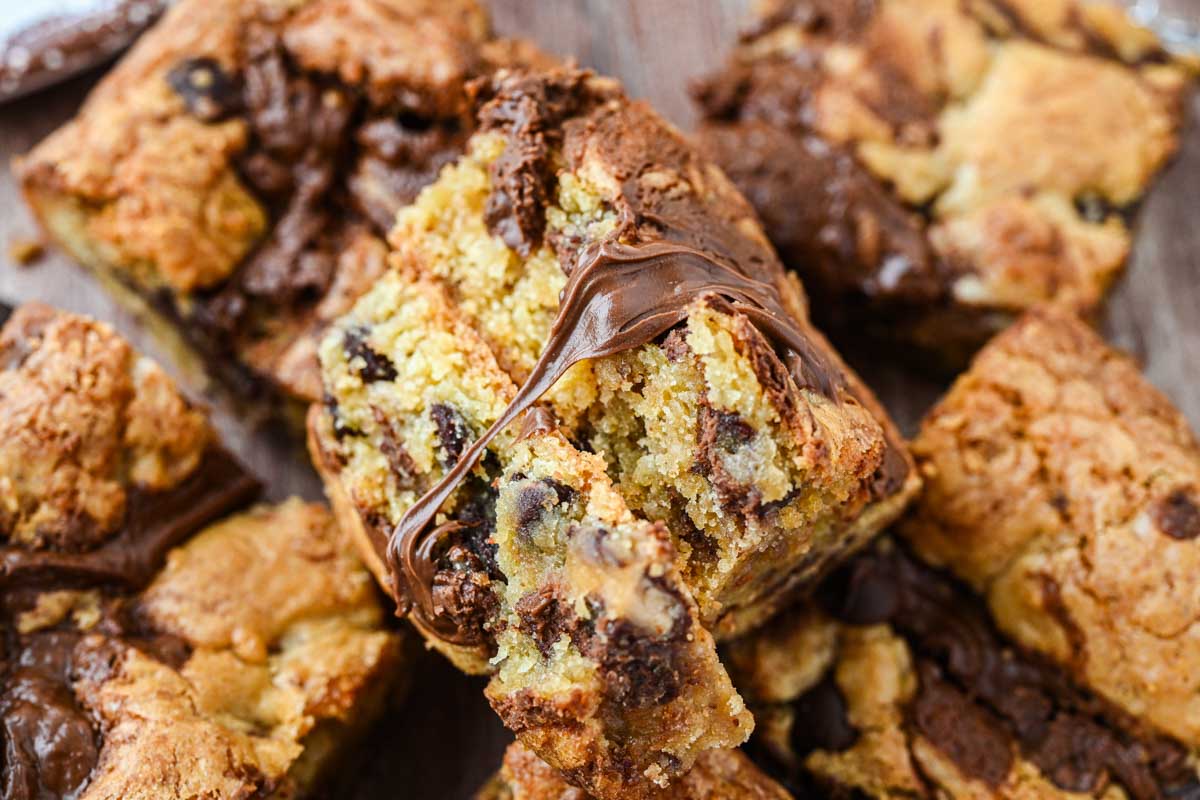 Closeup of a blondie pulled open to reveal a soft interior with melted Nutella stretching between the pieces.