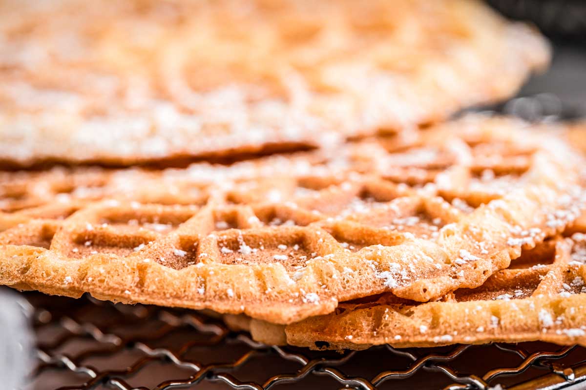 Detailed close up showing the crisp, lacy texture of a pizzelle dusted with powdered sugar.