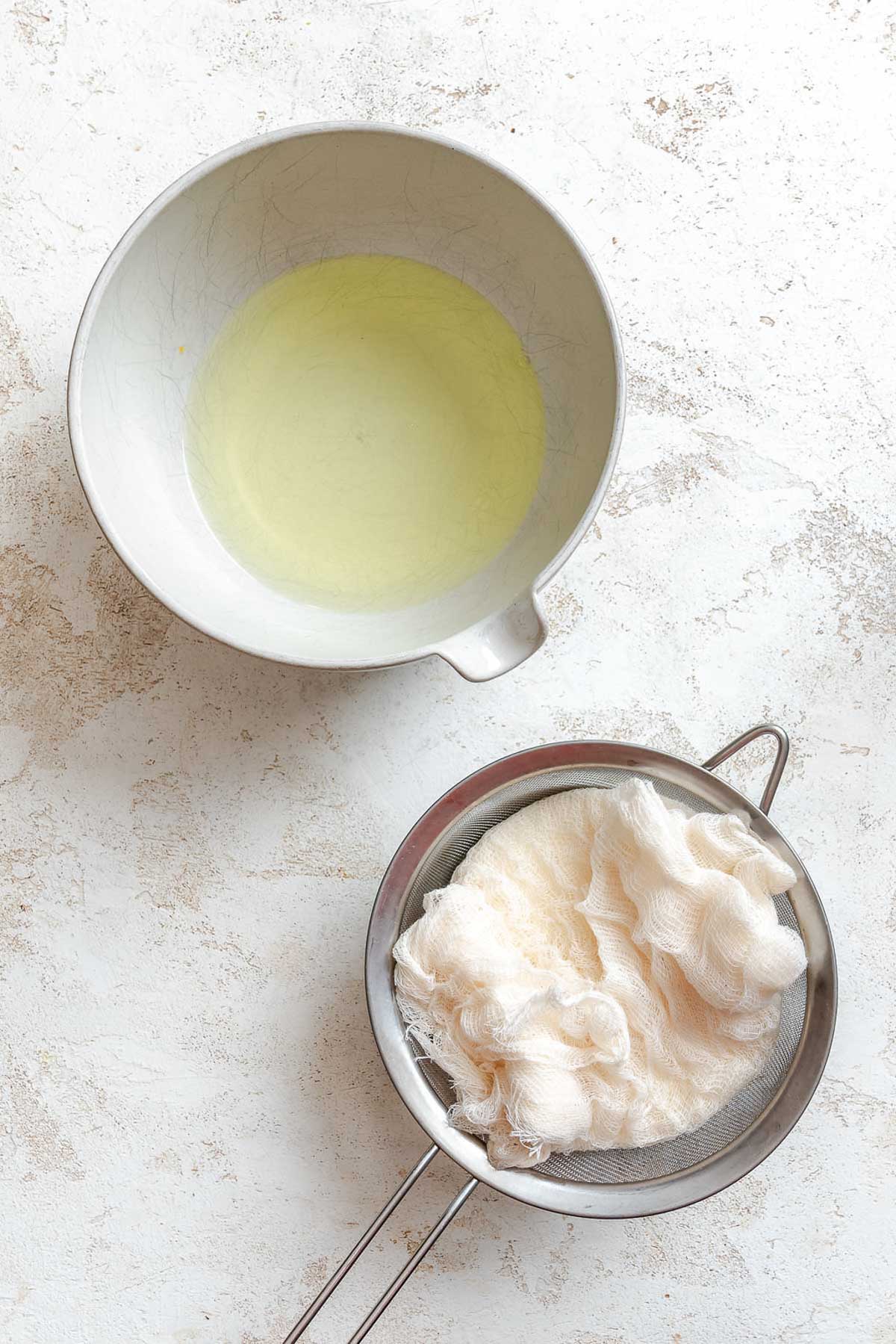 Overhead view showing liquid whey collected in a bowl beside strained yogurt.