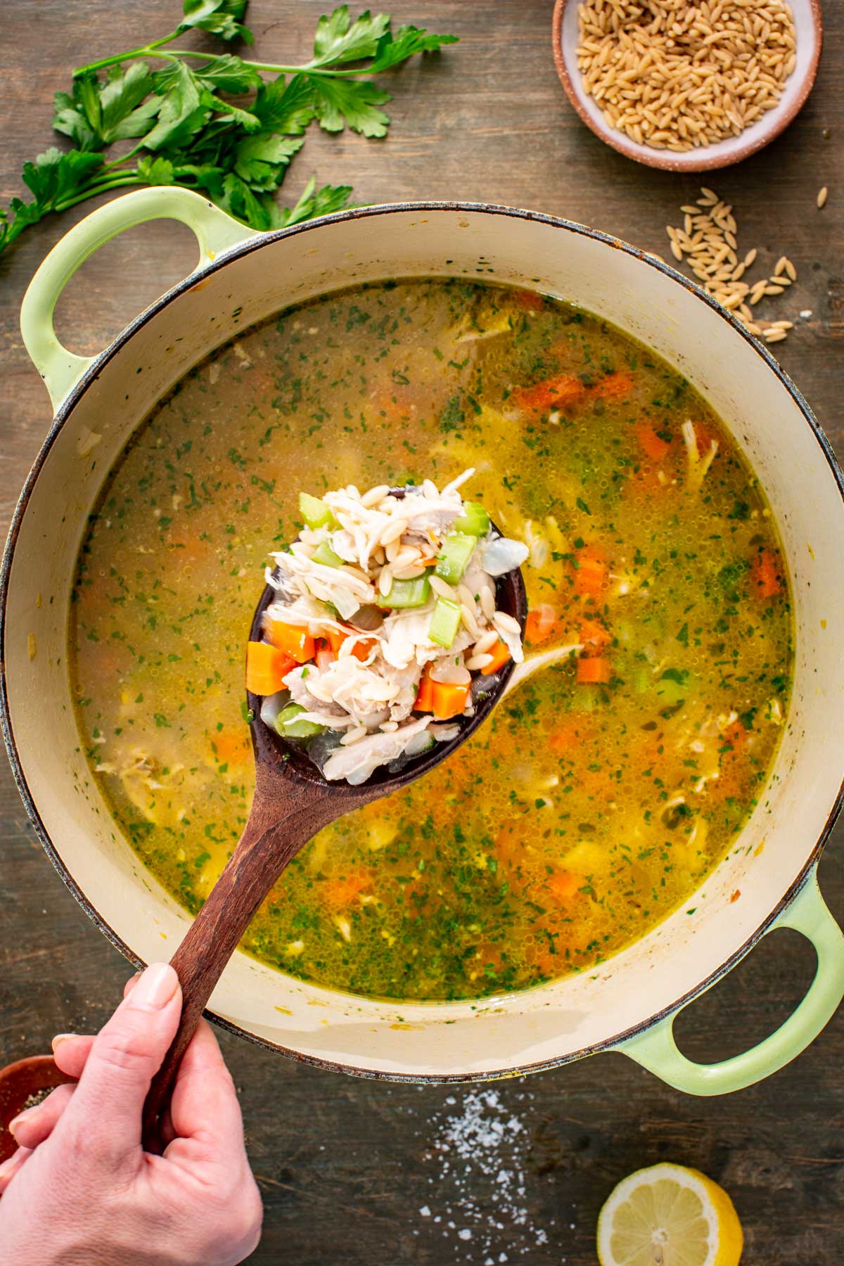 A ladle lifts a scoop of turkey, vegetables and orzo from the pot of soup.