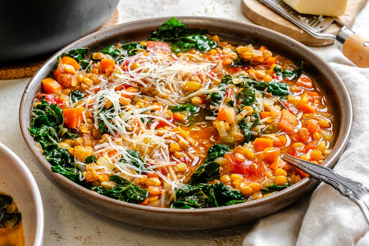 A bowl of lentil soup topped with freshly grated Parmesan cheese, ready to serve.