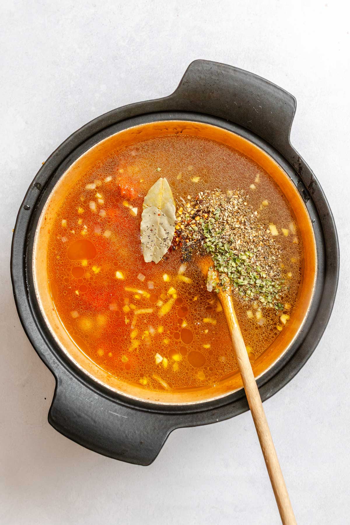 Lentils, crushed tomatoes, broth, bay leaf and dried seasonings stirred together in a Dutch oven.