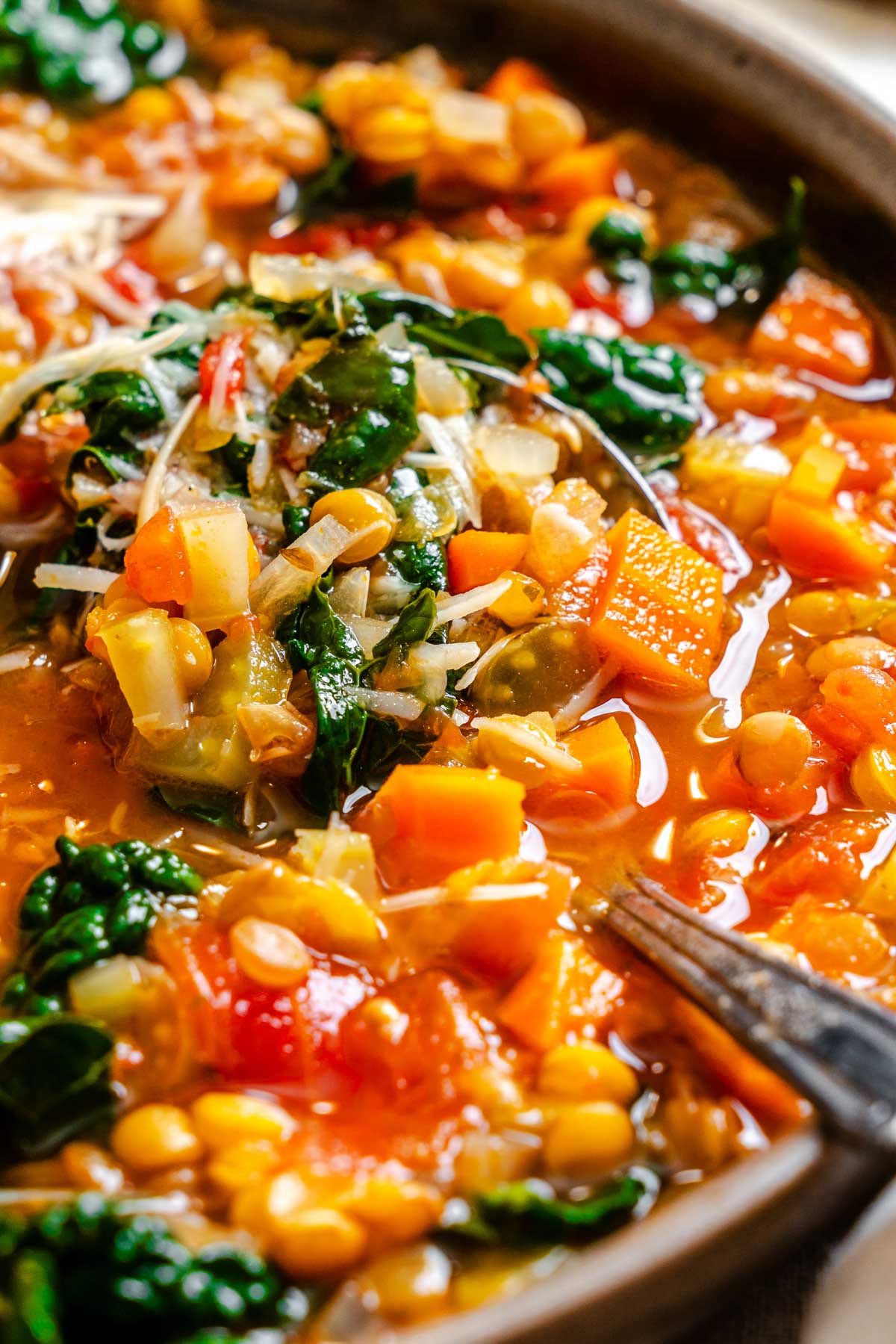 A close view of tender lentils, greens and vegetables in broth, showing texture and vibrant color.