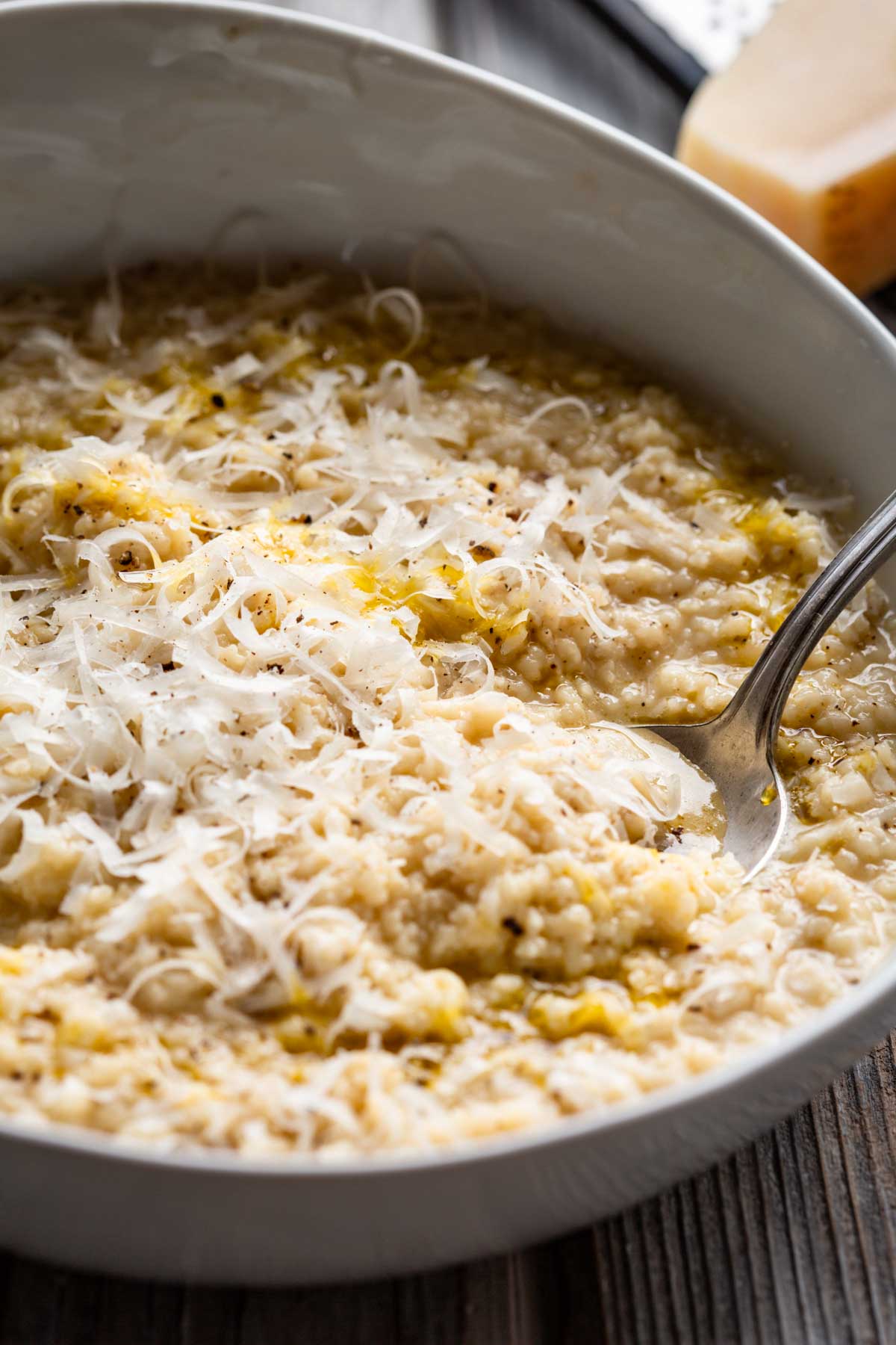 A close, detailed view of creamy pastina in a bowl, showing the soft grains, melted cheese and olive oil pooling on top.