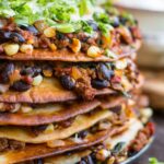 Close-up view showing crispy flour tortilla layers filled with ground beef, black beans, corn and spinach.