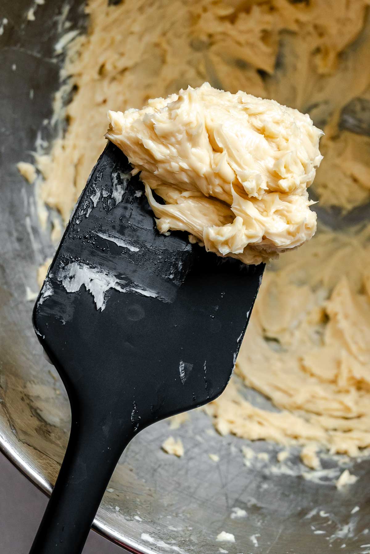 Close-up of fluffy whipped maple butter scooped onto a black rubber spatula, showing its smooth, spreadable texture.