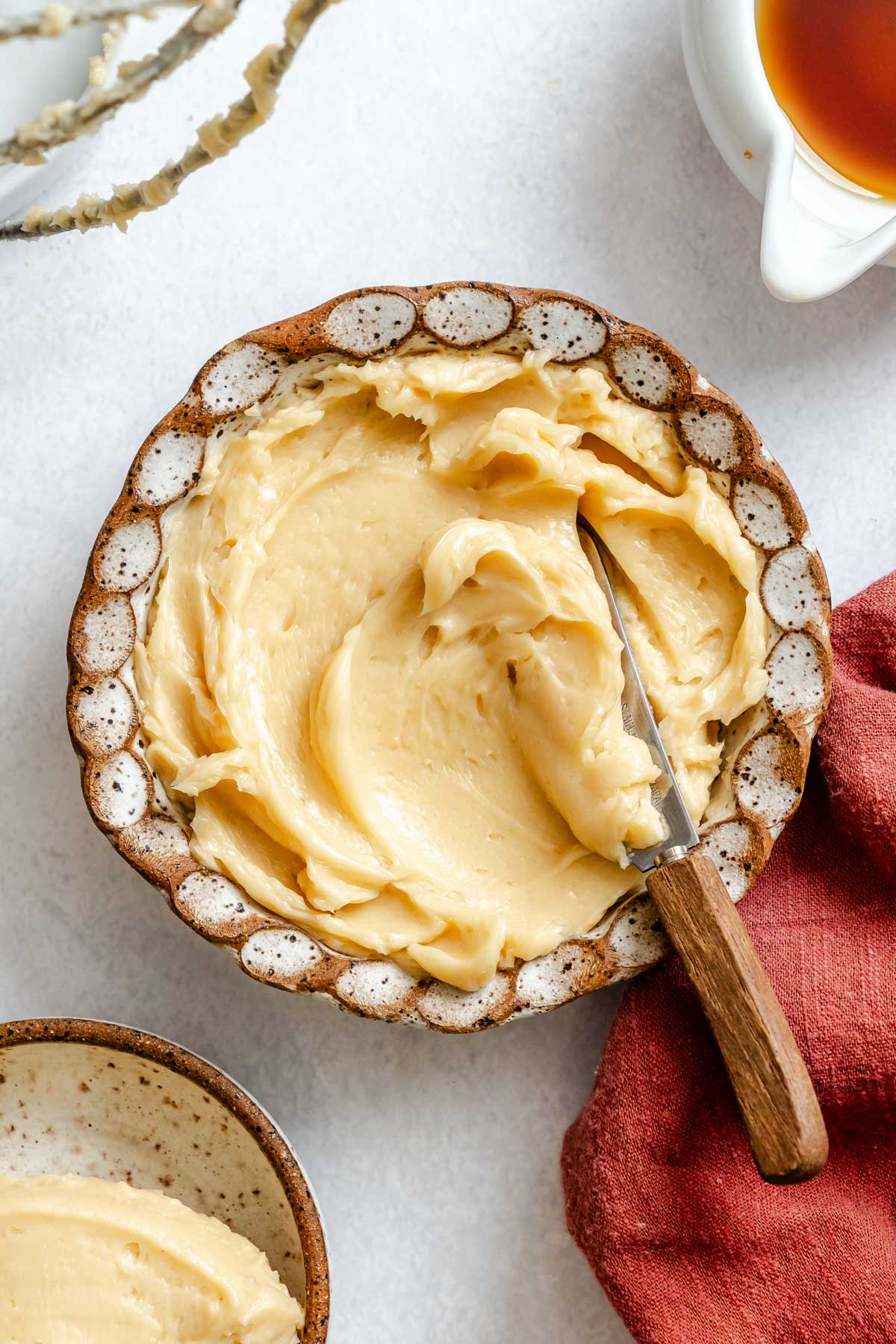 Whipped maple butter swirled into a shallow ceramic bowl with a butter knife resting on top, styled for serving.