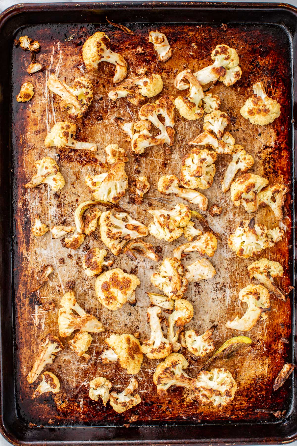 Golden brown roasted cauliflower florets caramelized on a sheet pan after roasting.
