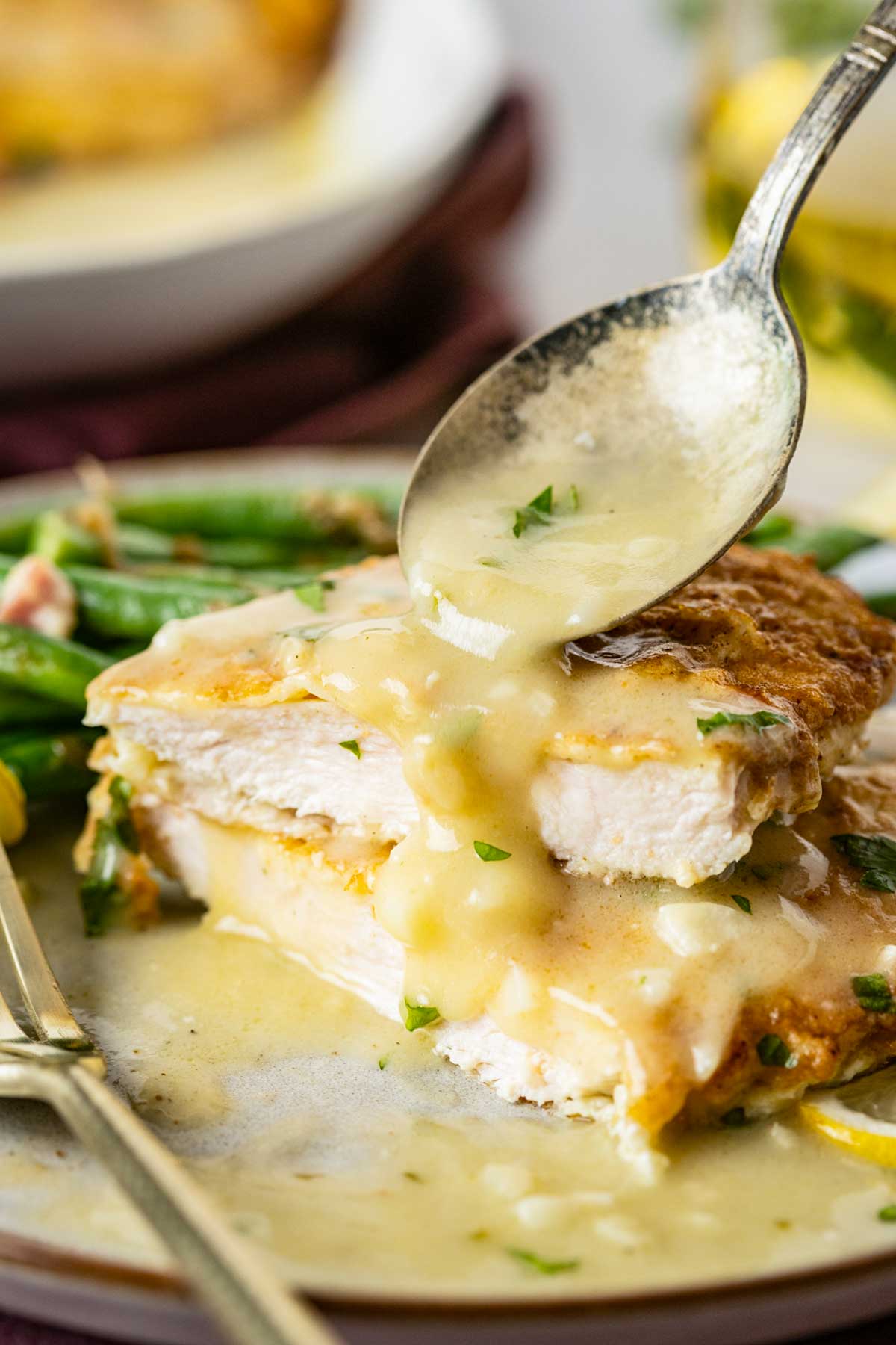 Close up of chicken francaise sliced open, showing the juicy interior and lemon butter sauce dripping over the cut edge.