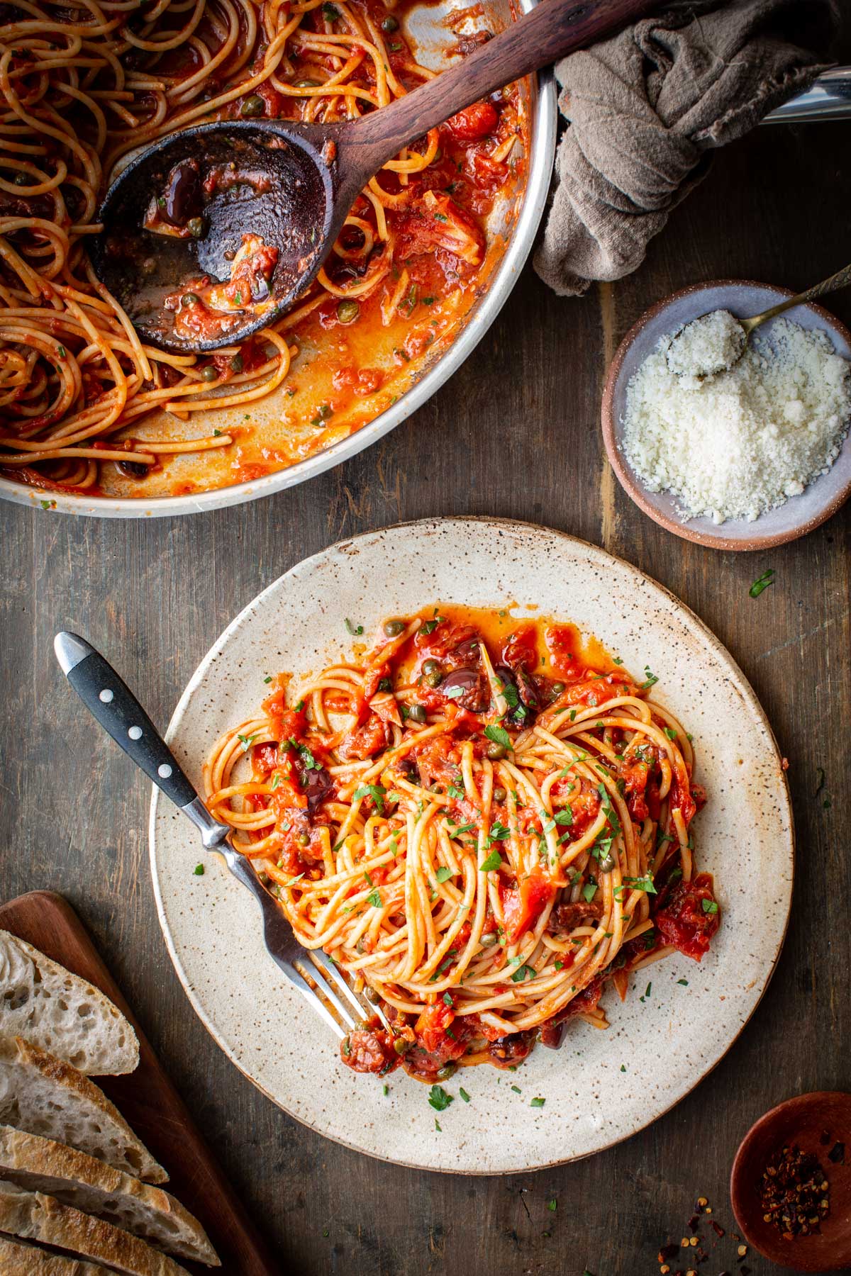 Finished spaghetti puttanesca topped with chopped fresh parsley in the pan.