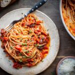 Spaghetti puttanesca served on a plate with visible olives, capers, and tomato sauce.